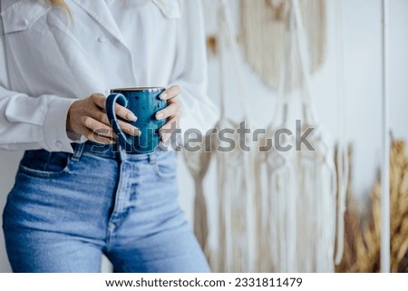 Close up of unrecognizable woman hands relaxing with cup of tea in a home atelier macrame workshop.