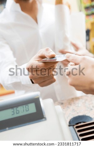 man doing shopping in a grocery store and paying by credit card