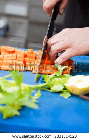 close-up of chef cutting some carrots on blue cutting board