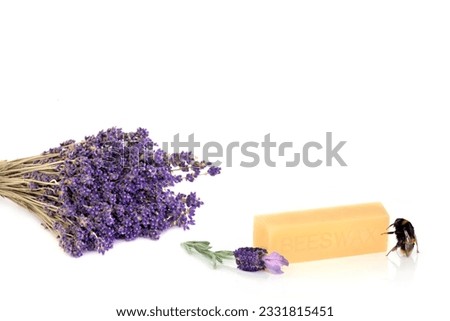Dried lavender herb in a bunch with fresh flowers and a bumble bee next to a beeswax block, over white background.