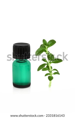 Aromatherapy essential oil glass bottle with a peppermint herb leaf sprig, over white background.