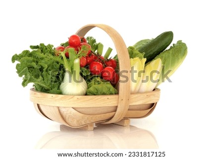 Fresh selection of salad vegetables, lettuces and cherry tomatoes on the vine in a wooden basket, over white background.