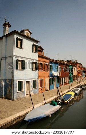 Buildings and boats on a canal in Venice, Italy, under blue sky. Vertical shot.