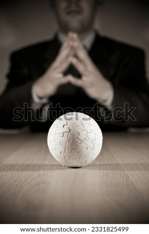 A businesman pondering with focus on a puzzle globe.