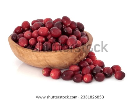 Cranberry fruit in an olive wood bowl and scattered, isolated over white background. Used at christmas and thanksgiving as an accompaniment to turkey.