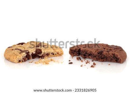 Chocolate chip and all butter cookies with bites taken out of both and scattered crumbs, over white background.