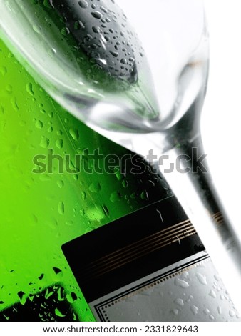 Close-up of a cold wet bottle of alcoholic drink with glasses -focus on bottle-