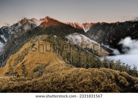 Beautiful mountain landscape with snow peak, grassland and forest in sunrise in Taiwan, Asia.