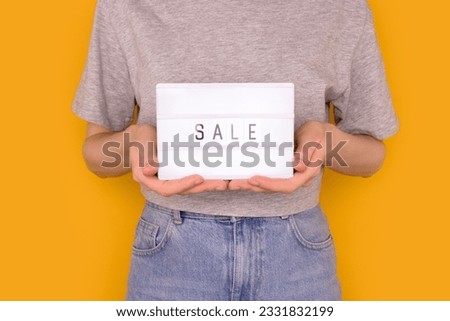 Word Sale. Woman hold in hands lightbox with letters in front of yellow background. 