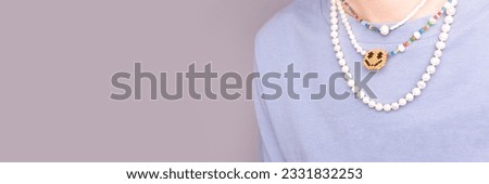 Banner with pearl beads on a young woman in a t-shirt in front of blue background. Selective focus. Place for text.