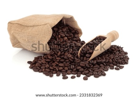 Coffee beans in a wooden scoop and spilling out from a hessian bag, over white background.
