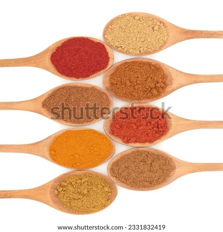 Spice selection of paprika, turmeric, mixed spice, mild and hot curry powder, cayenne pepper, chinese five spice and ginger in eight wooden spoons over white background.