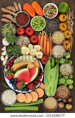 Healthy diet food concept with a selection of fruit, vegetables, seeds, grains, cereals, herbs and spices with foods high in vitamins, minerals, anthocyanins, antioxidants and fiber on oak background