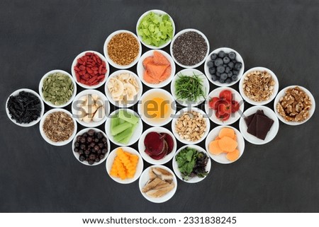 Health food concept to boost brain power and promote memory in porcelain bowls on slate background. Foods high in antioxidants, anthocyanains, vitamins and minerals.
