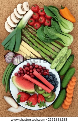 Health food for healthy eating concept with fresh vegetables and fruit on cork background, high in antioxidants, anthocyanins, minerals, vitamins and dietary fiber. Top view.