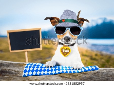 bavarian jack russell dog holding a beer mug outdoors by the river and mountains , ready for the beer party celebration festival in munich