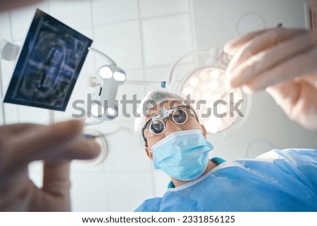 Surgeon dentist in special lenses is in the operating room