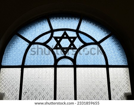 A stained glass window in a Singapore synagogue features a Star of David in blue and white glass as an architectural feature. Royalty-Free Stock Photo #2331859655