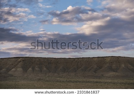 The relief of mountain hills at sunset illumination in the evening against the background of rain clouds, a minimalistic evening mountain range