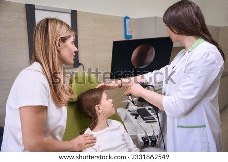 Girl is sitting in green armchair at appointment with otolaryngologist