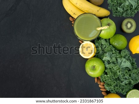 Healthy living concept with a glass of green smoothie with fruit and vegetables including Kale and citrus fruits.