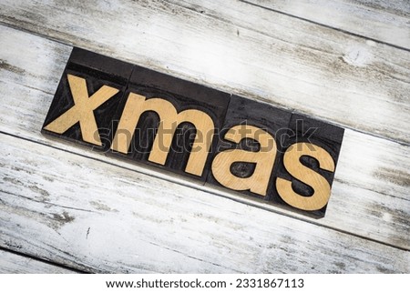 The word -xmas- written in wooden letterpress type on a white washed old wooden boards background.