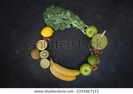 Healthy living concept with a glass of green smoothie surrounded fruit and vegetables in a circle shape with room for text.