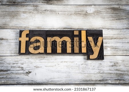 The word -family- written in wooden letterpress type on a white washed old wooden boards background.
