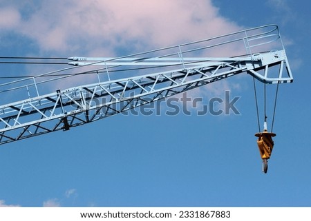 Construction crane arm with hook against blue sky background Royalty-Free Stock Photo #2331867883