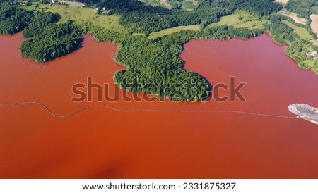 Red lake and green forest. Tailing pond. Polluted lake in nature. Environmental impact of production of aluminum. Bauxite residue. Dump pond containing toxic waste. Royalty-Free Stock Photo #2331875327