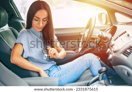 Safety and car driving concept. Close up photo of smiling young woman driver while she fastening seat belt. Royalty-Free Stock Photo #2331875615