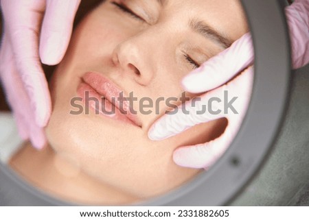 Beautician examines the nasolabial folds of patient after beauty injections Royalty-Free Stock Photo #2331882605