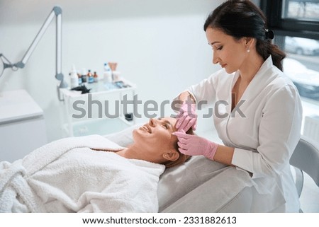 Cosmetologist uses a special marker to mark the working areas Royalty-Free Stock Photo #2331882613