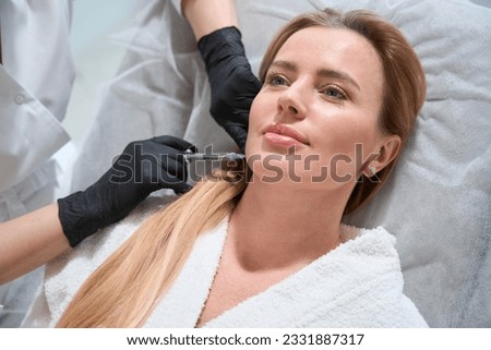 Female receives a rejuvenating injection in her cheeks Royalty-Free Stock Photo #2331887317
