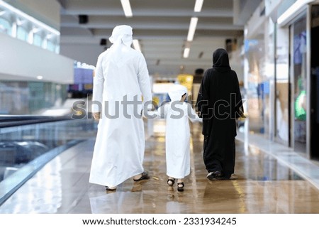 Arab Emirati family walking together at indoor shopping mall, station or airport concept. Arabic father, mother and son bonding ideal for Middle Eastern people concept Royalty-Free Stock Photo #2331934245