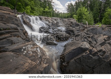 Wilson's Falls, a Muskoka waterfall just outside of Bracebridge, Ontario flows over large rocks. Royalty-Free Stock Photo #2331941363