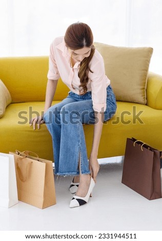 Portrait isolated cutout studio shot of Asian cheerful female client customer shopper in casual outfit sitting on cozy sofa take break buying stuff in paper shopping bags in store on white background. Royalty-Free Stock Photo #2331944511