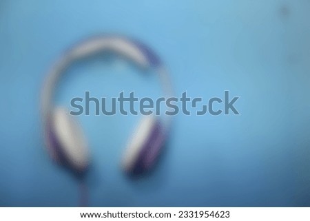 Blurred defocused photo of A purple headset hangs on a blue wall, for background template. Out of focus, noise, over or under exposure, over compressed effect.