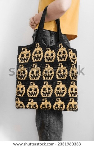 Girl with handmade crochet Halloween bag. Black yellow eco friendly bag with pumpkin pattern.