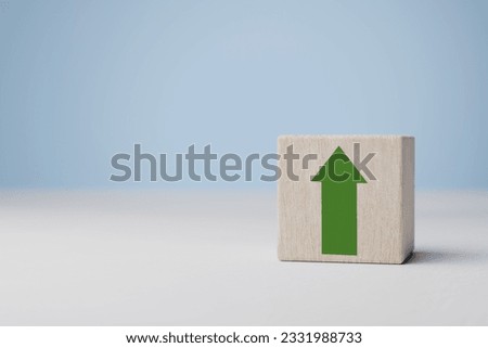 Green increasing up arrow on wooden cube block, It is symbol of business investment growth concept. Growth graph of financial indicators and economy on wooden cubes. Business success growing.