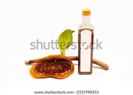 Honeycomb on a branch and honey in a plastic bottle on a white background
