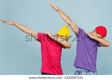 Young cool couple two friends men wear casual clothes together doing dab hip hop dance hands move gesture youth sign hide cover face isolated on pastel plain light blue cyan background studio portrait Royalty-Free Stock Photo #2332007161