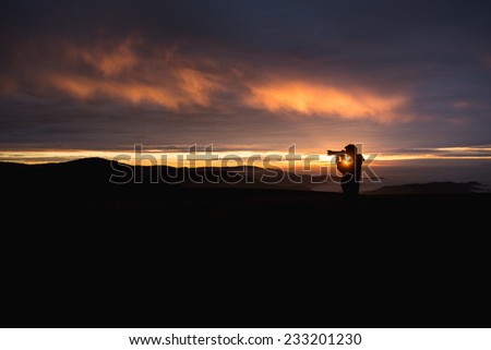 silhouetted photographer in sunset sky
