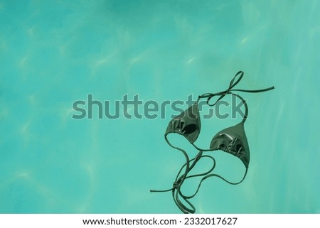 Summer rest concept. Top view photo of green bikini isolated pastel blue water background. Summer travel concept. Bikini, swimsuit. Top view, copy space. 