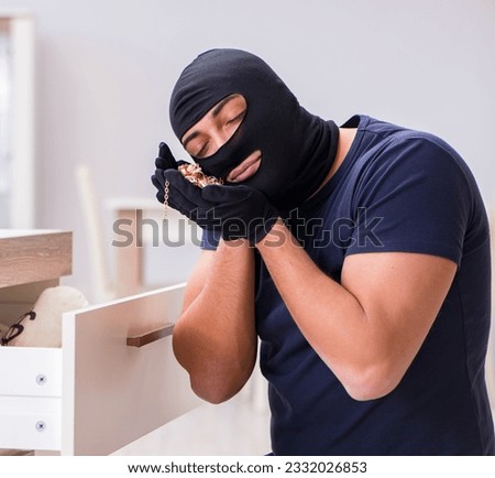 Robber wearing balaclava stealing valuable things Royalty-Free Stock Photo #2332026853
