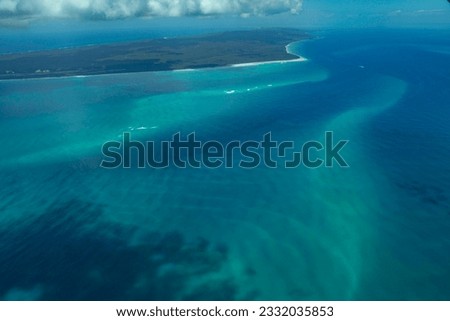 Flying over the turquoise blue ocean in Australia. An island surrounded by beautiful azure waters. Photo taken from a plane. Sand ripples and shallow water patterns in the tropics.