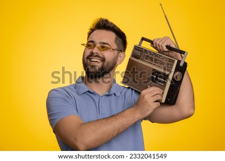 Happy excited man using retro tape record player to listen music, disco dancing of favorite track, having fun, entertaining, fan of vintage technologies. Handsome guy isolated on yellow background