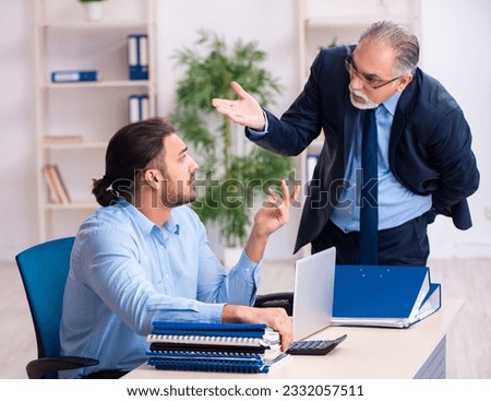 Old boss and his young assistant in the office Royalty-Free Stock Photo #2332057511