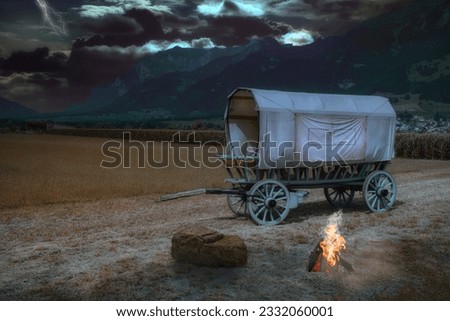 Covered wagon near Landquart in a thunderstorm atmosphere and campfire Royalty-Free Stock Photo #2332060001