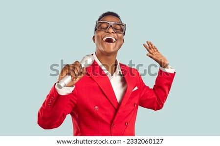 African singer isolated on light background. Stylish ethnic MC or showman taking part in karaoke party, talent show, or retro funk night club event, standing on stage, holding microphone and singing Royalty-Free Stock Photo #2332060127